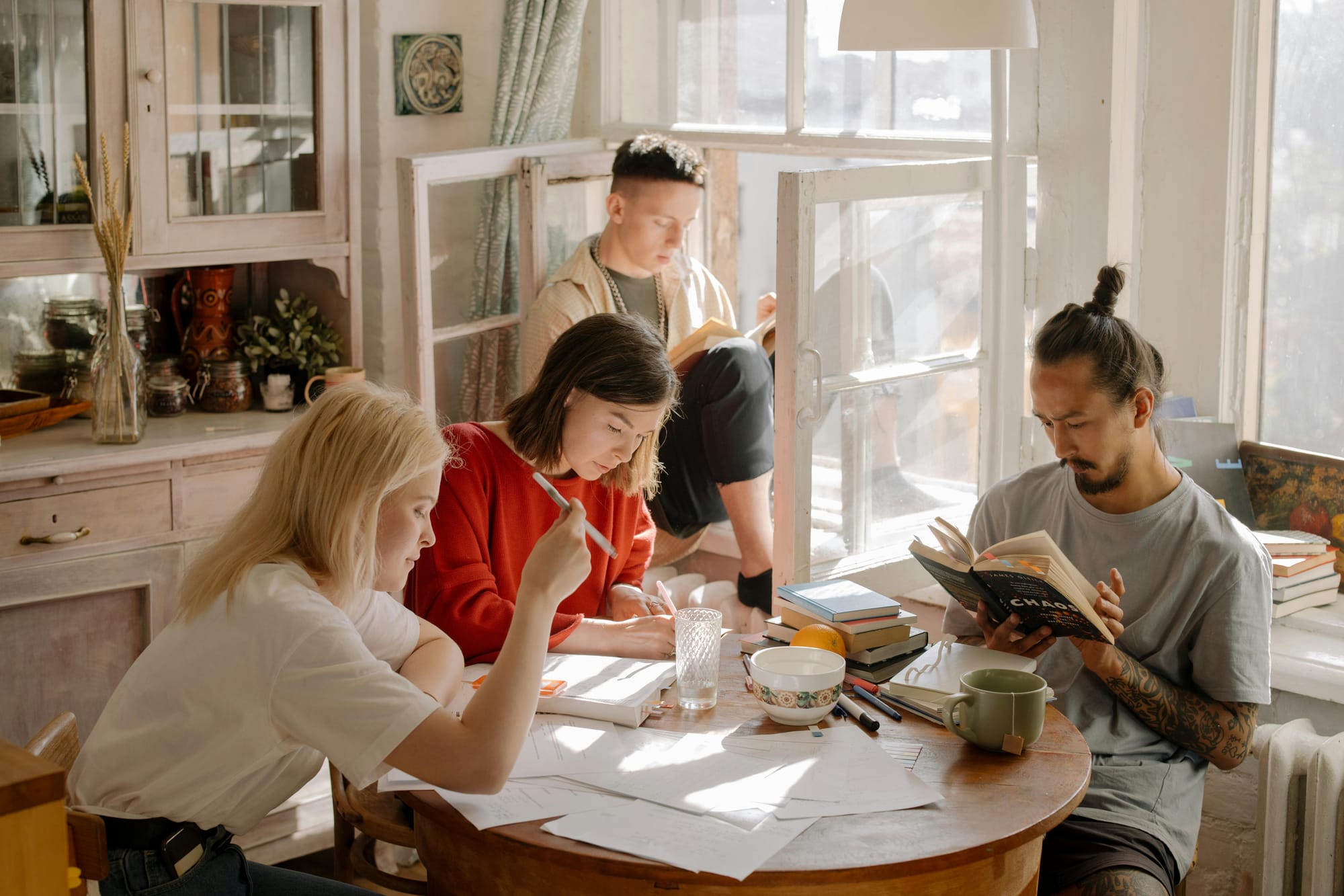 Um grupo de 4 jovens estudando e lendo livros