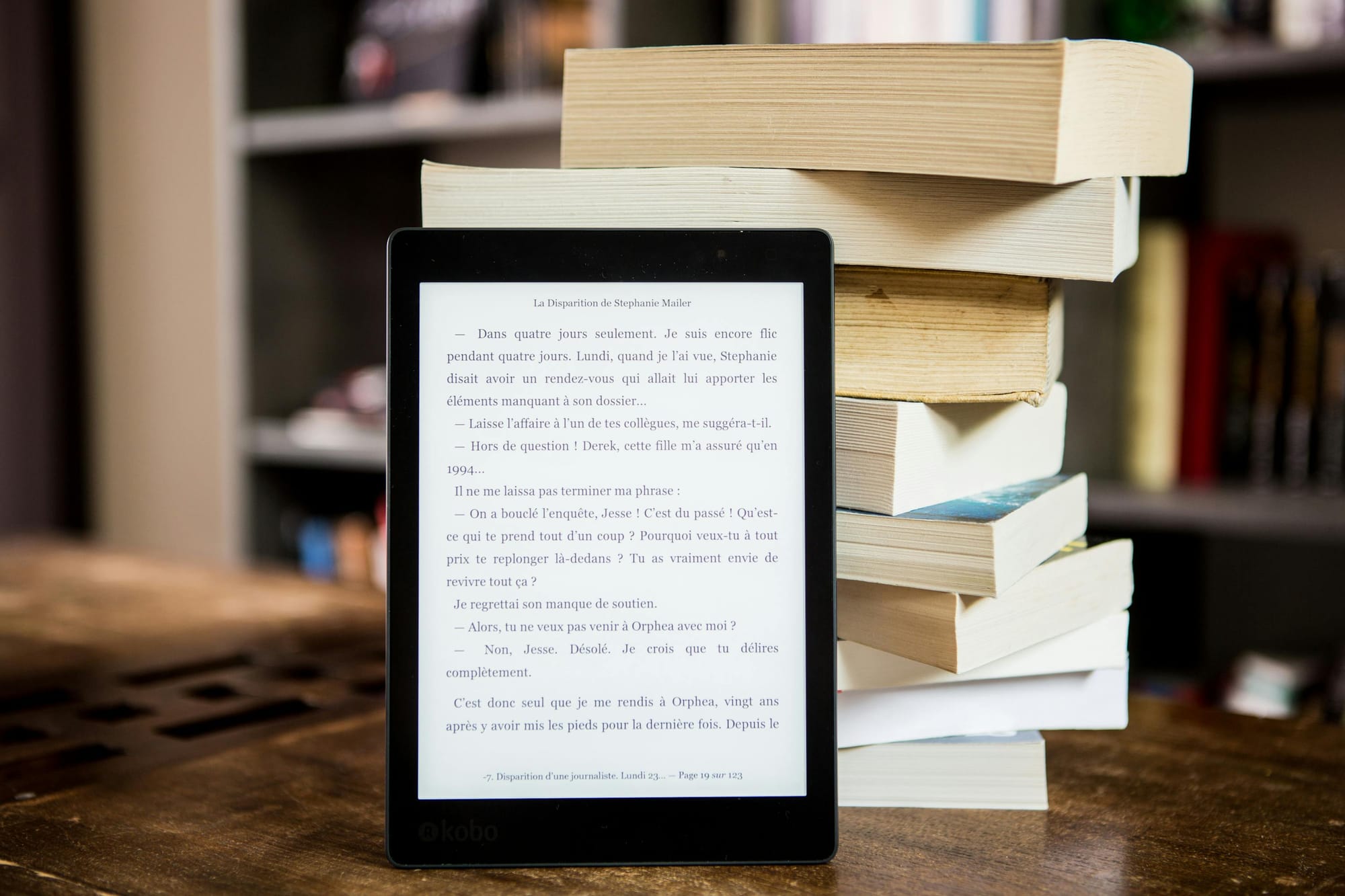 Na imagem vemos alguns livros e um kindle, para ilustrar que a leitura pode ser de diferentes maneiras