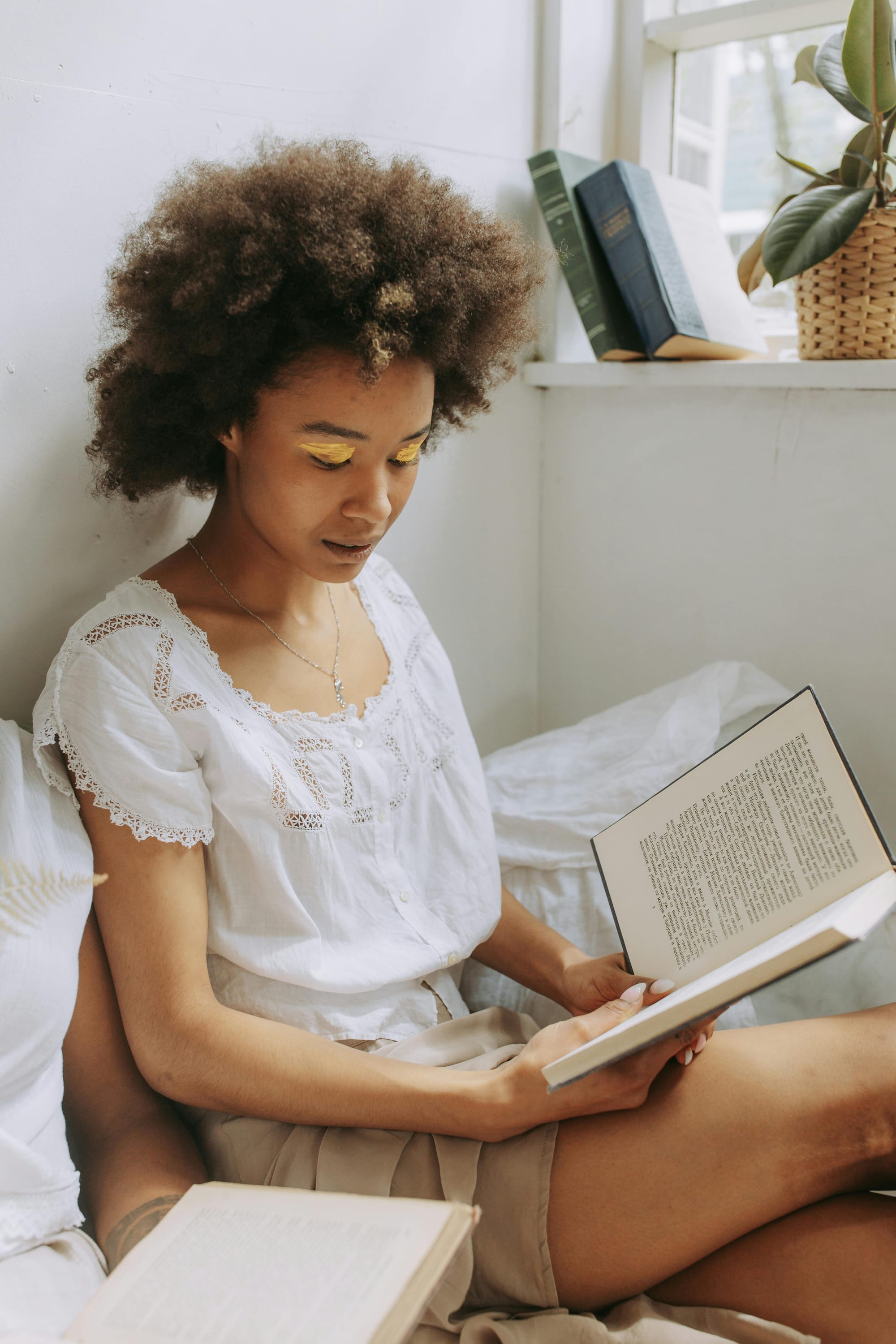 Jovem menina lendo um livro próximo da janela