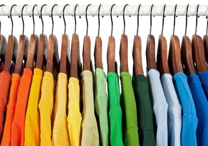 Camisetas penduradas em cabide por ordem de cor